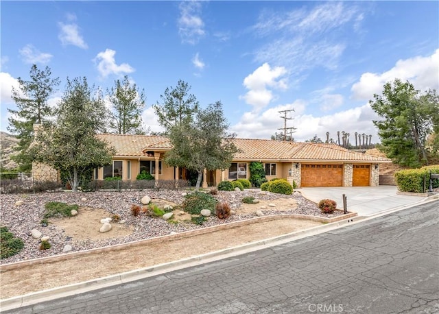 ranch-style home featuring a garage, a tiled roof, stone siding, concrete driveway, and stucco siding