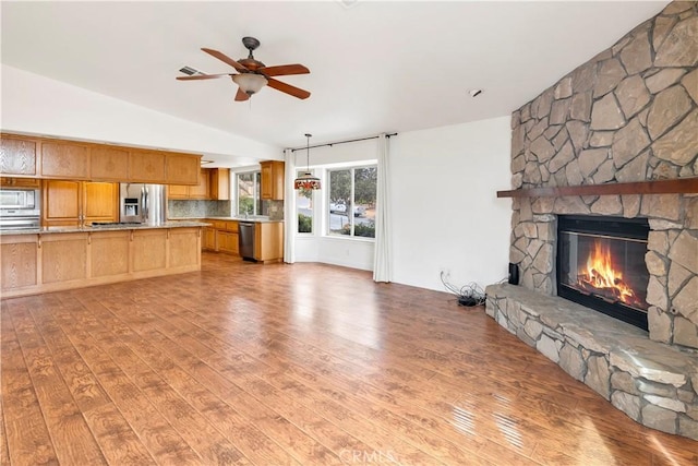 unfurnished living room with vaulted ceiling, a fireplace, and light wood-style flooring