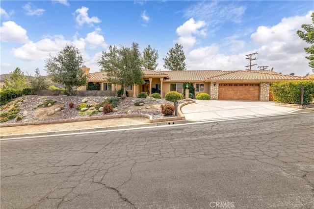 view of front of property with a garage, concrete driveway, stone siding, a tile roof, and a chimney