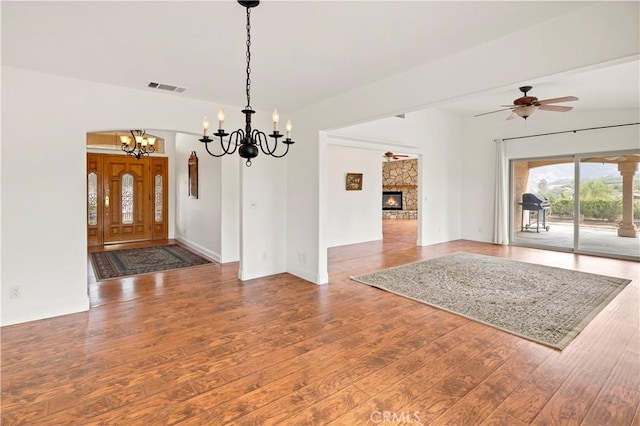 interior space with a stone fireplace, hardwood / wood-style flooring, visible vents, and a ceiling fan