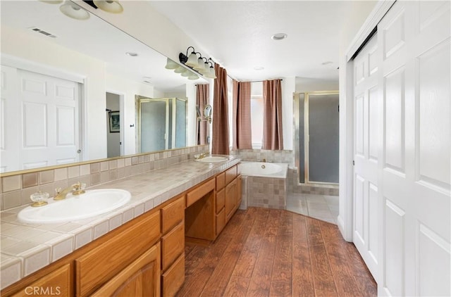 full bathroom with hardwood / wood-style flooring, a sink, visible vents, and a shower stall