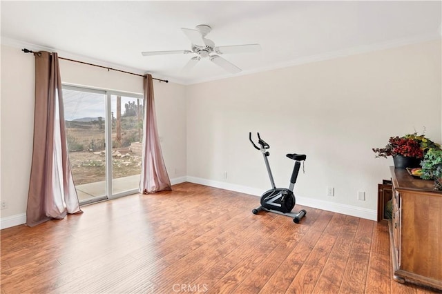 workout room featuring ornamental molding, a ceiling fan, baseboards, and wood finished floors