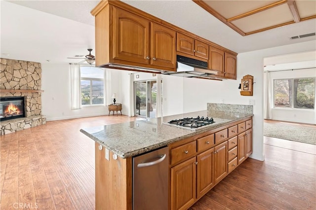 kitchen featuring a fireplace, visible vents, stainless steel gas stovetop, open floor plan, and light stone countertops