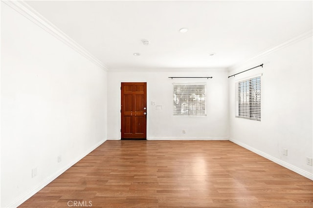 unfurnished room with light wood-style floors, ornamental molding, and baseboards