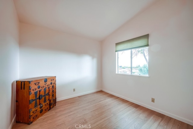 unfurnished room featuring lofted ceiling, baseboards, and wood finished floors