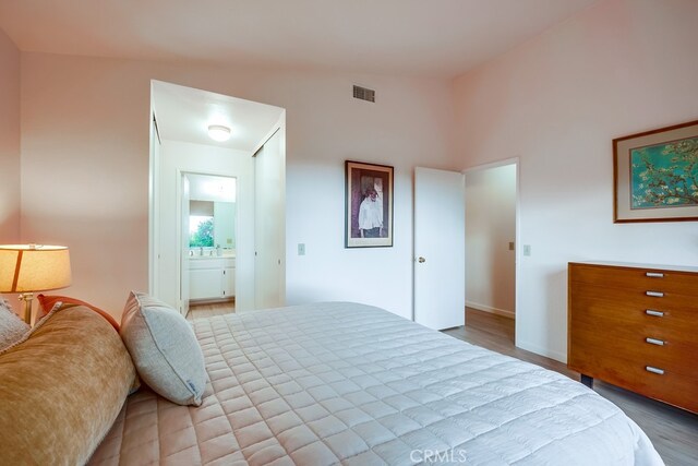 bedroom featuring visible vents, ensuite bath, and wood finished floors