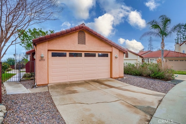 garage featuring concrete driveway and fence