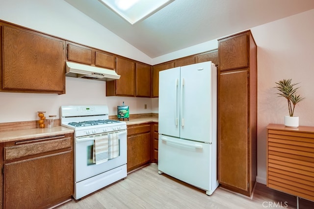 kitchen with lofted ceiling, under cabinet range hood, white appliances, light wood finished floors, and brown cabinetry