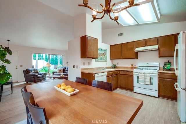 kitchen with white appliances, under cabinet range hood, visible vents, and brown cabinets