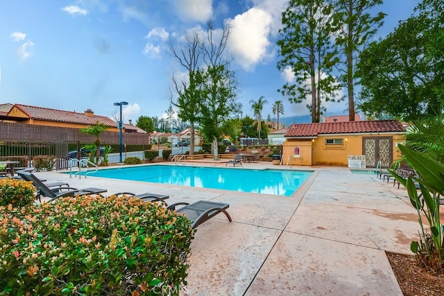 community pool with french doors, a patio area, and fence