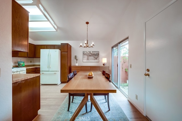 dining space with lofted ceiling, light wood-type flooring, and a notable chandelier