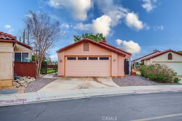 view of front of house with stucco siding, fence, a garage, driveway, and a tiled roof