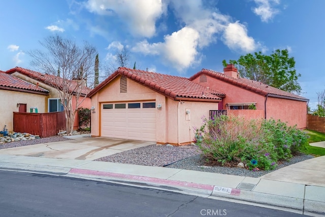 mediterranean / spanish-style home with a tiled roof, a chimney, fence, and stucco siding