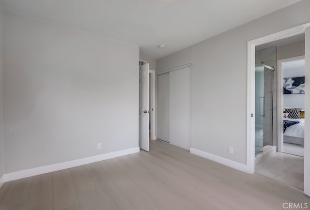 unfurnished bedroom featuring a closet, light wood-style flooring, and baseboards