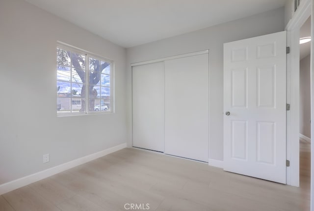 unfurnished bedroom with light wood finished floors, a closet, and baseboards