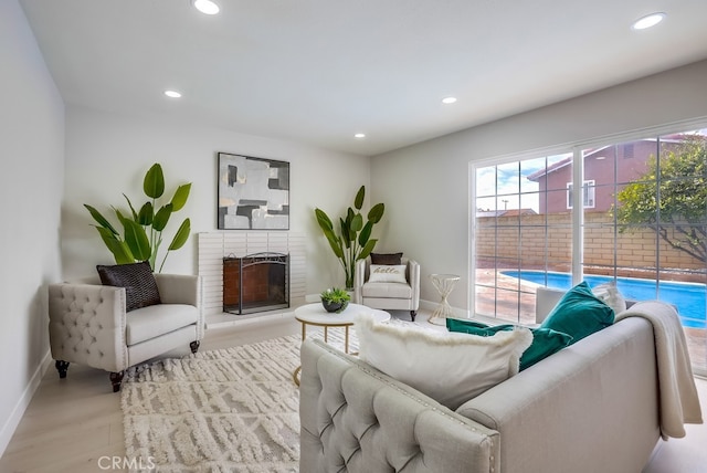 living area with baseboards, a brick fireplace, and recessed lighting