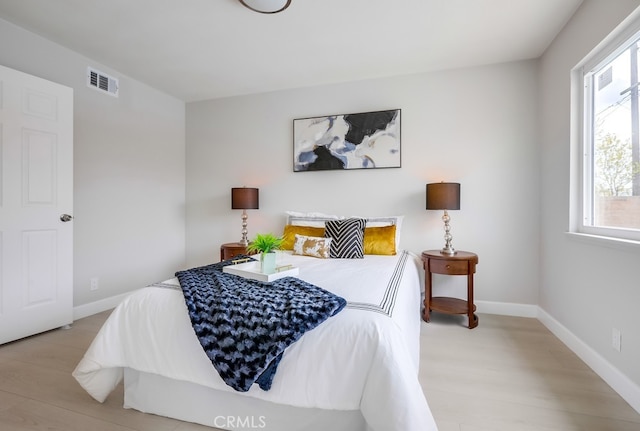 bedroom with light wood-type flooring, visible vents, and baseboards