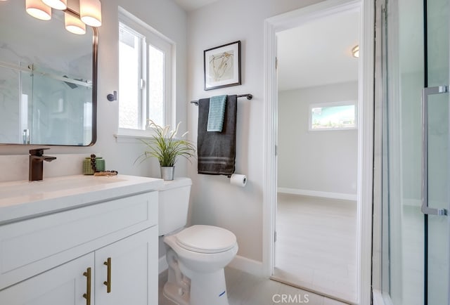 full bathroom with toilet, a marble finish shower, baseboards, and vanity