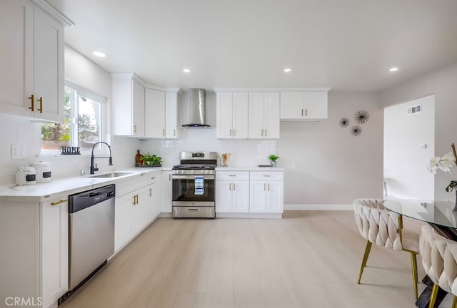 kitchen featuring a sink, visible vents, appliances with stainless steel finishes, backsplash, and wall chimney exhaust hood