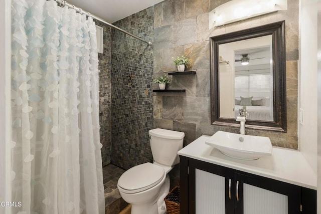 full bath with a tile shower, tile walls, toilet, and vanity