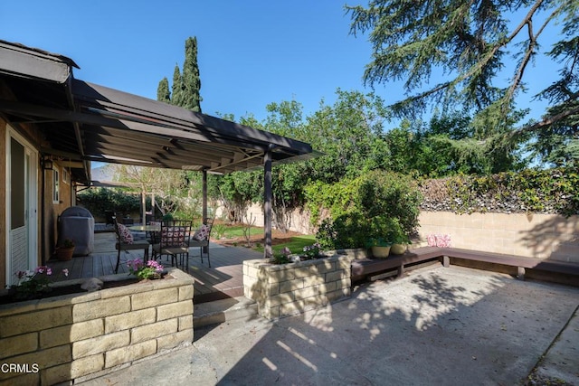 view of patio featuring outdoor dining space, fence, a wooden deck, and a pergola