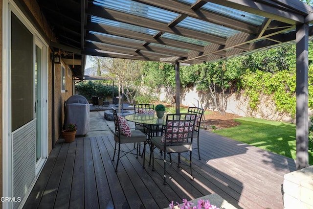 deck featuring outdoor dining area, grilling area, a fenced backyard, and a lawn