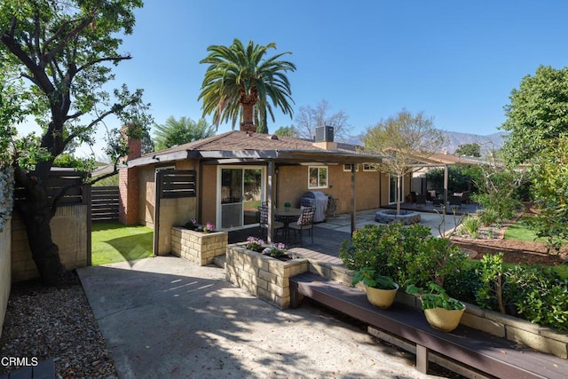 rear view of house featuring a patio, a chimney, central air condition unit, a mountain view, and fence