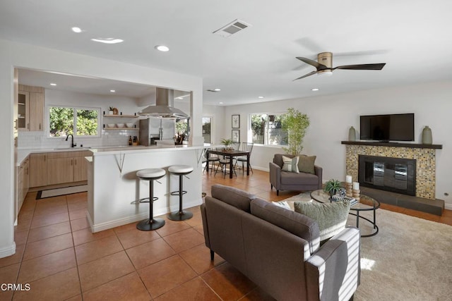 living area with a wealth of natural light, visible vents, a tiled fireplace, and light tile patterned flooring