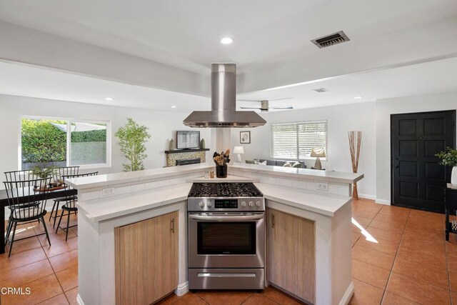 kitchen featuring a wealth of natural light, stainless steel range with gas cooktop, visible vents, and exhaust hood