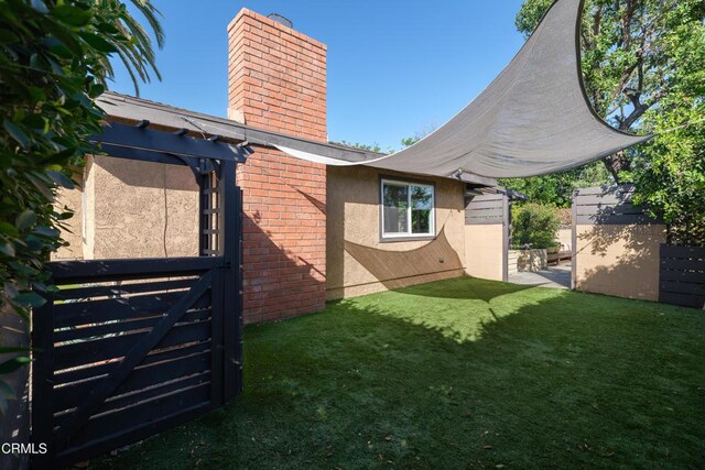 exterior space with a lawn, a chimney, fence, and stucco siding