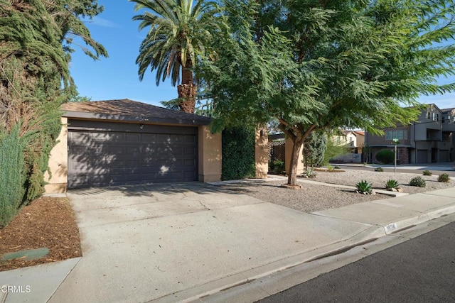 view of front of house featuring driveway, an outdoor structure, and stucco siding