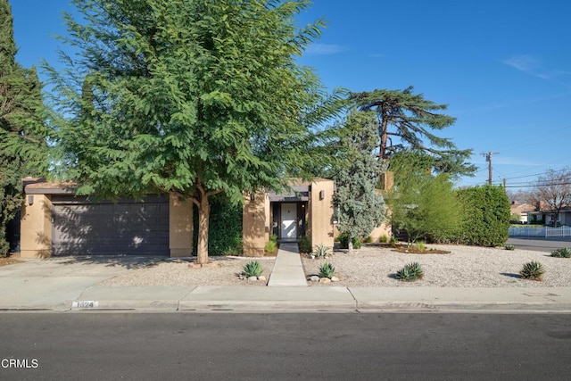 view of front of home featuring driveway, an attached garage, and stucco siding