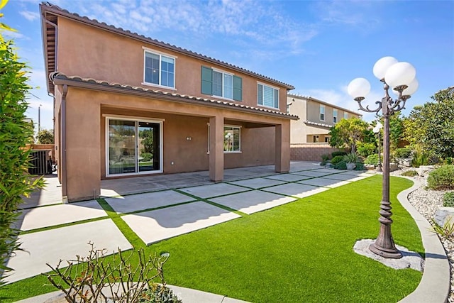 back of property with a lawn, a tile roof, fence, a patio area, and stucco siding