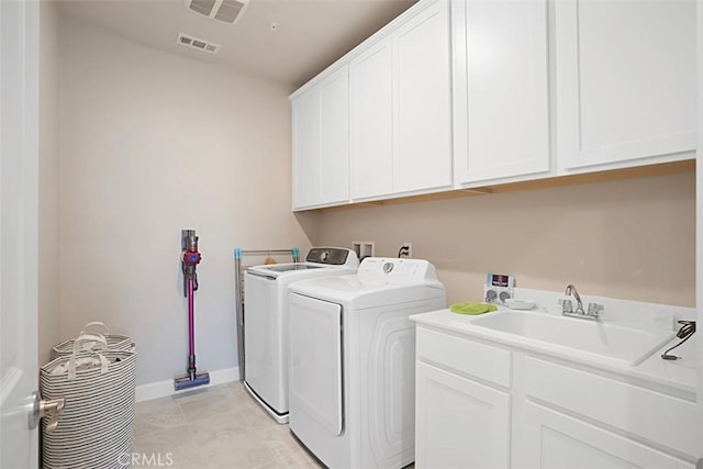 clothes washing area with washer and dryer, cabinet space, a sink, and visible vents