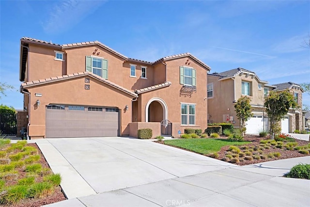 mediterranean / spanish home featuring an attached garage, driveway, a tiled roof, and stucco siding