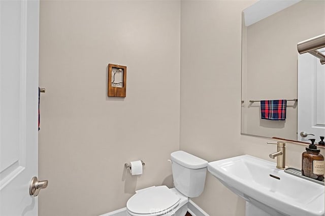 bathroom with baseboards, a sink, and toilet