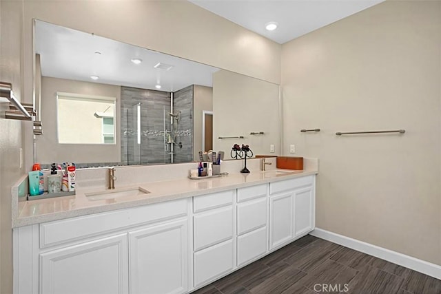 full bath featuring a shower stall, baseboards, a sink, and wood finish floors