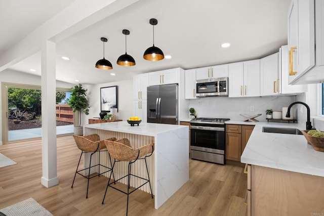 kitchen featuring a kitchen island, a breakfast bar area, a sink, stainless steel appliances, and backsplash