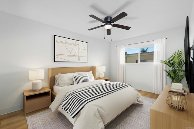 bedroom featuring a ceiling fan, light wood-style flooring, and baseboards