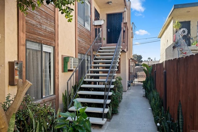 exterior space featuring stairs, fence, and stucco siding