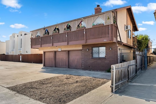 view of front facade with brick siding, a chimney, concrete driveway, fence, and a garage