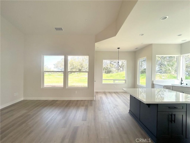 unfurnished living room with recessed lighting, visible vents, light wood-style floors, a sink, and baseboards