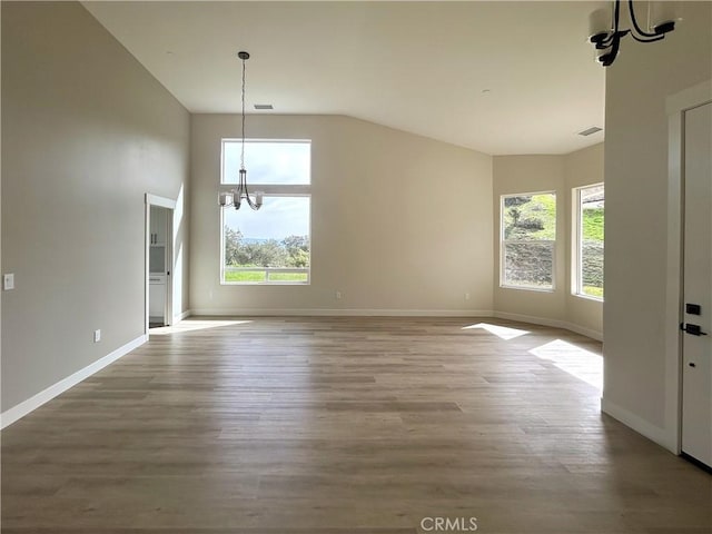 interior space featuring visible vents, a notable chandelier, baseboards, and wood finished floors