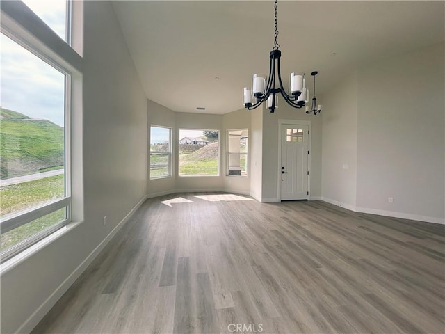 interior space featuring visible vents, light wood-style flooring, a high ceiling, a chandelier, and baseboards