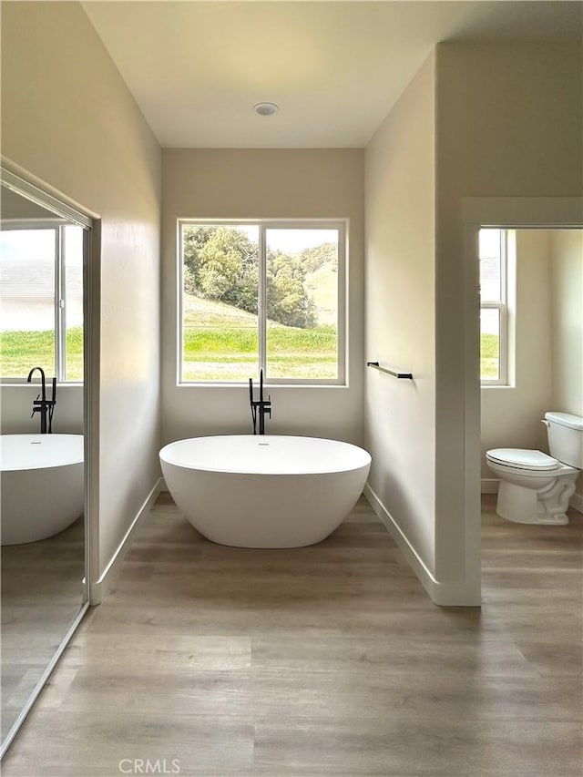 full bathroom featuring toilet, a wealth of natural light, and wood finished floors