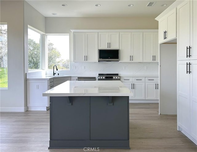 kitchen with appliances with stainless steel finishes, a center island, a healthy amount of sunlight, and a sink