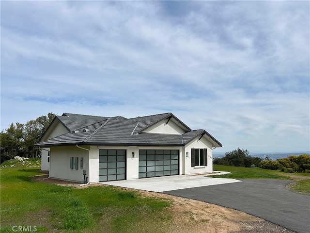 view of front facade featuring driveway, a tiled roof, an attached garage, and stucco siding