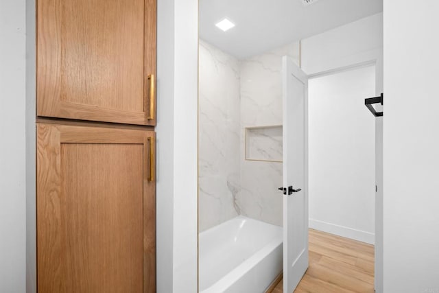 bathroom featuring shower / bathing tub combination, wood finished floors, and baseboards