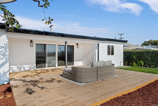 back of property featuring a deck, an outdoor hangout area, and stucco siding