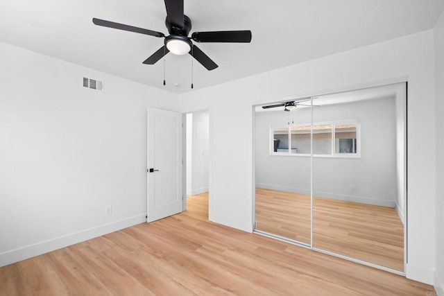 unfurnished bedroom featuring light wood-style floors, a closet, visible vents, and baseboards